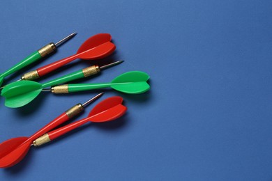 Photo of Colorful dart arrows on blue background, flat lay. Space for text