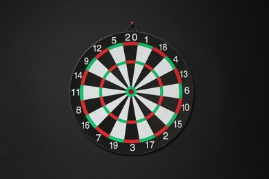 Photo of One dart board hanging on black wall