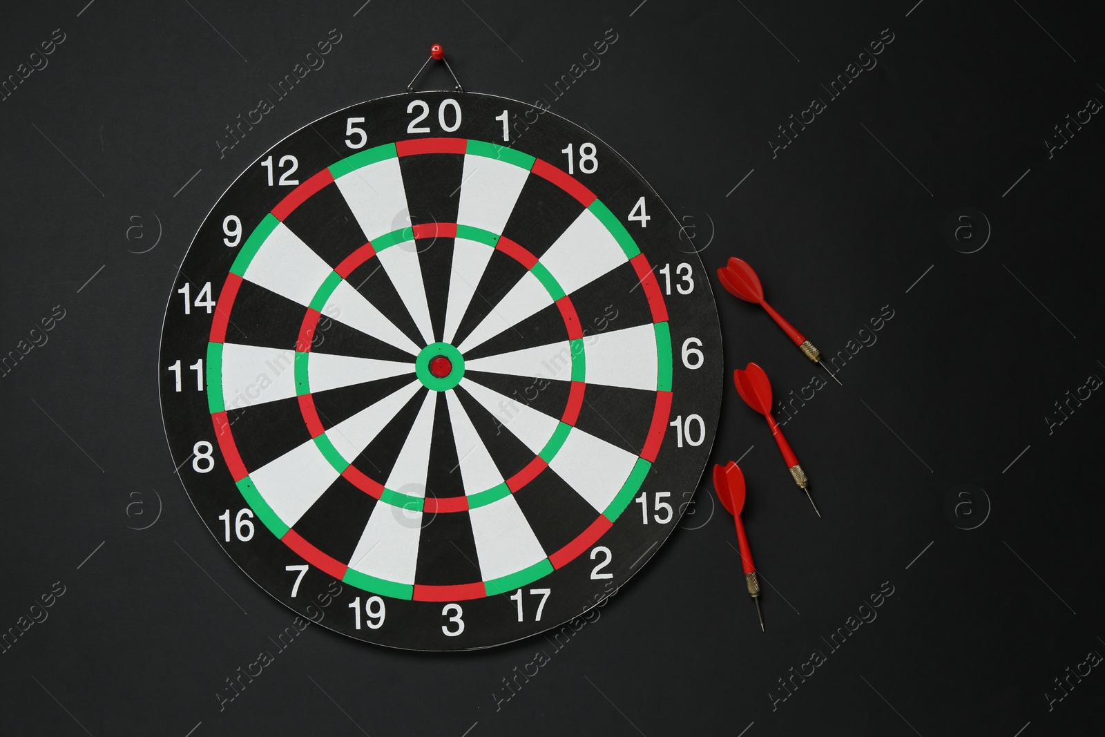 Photo of Dart board and red arrows on black background, flat lay