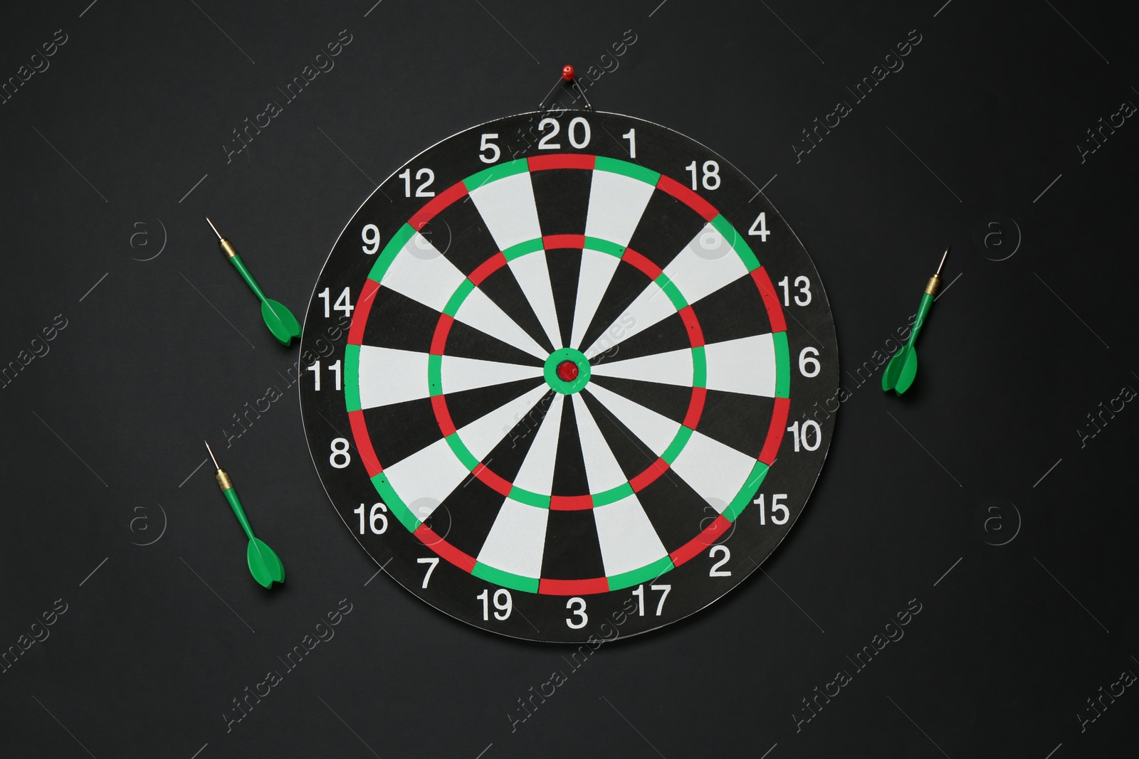 Photo of Dart board and green arrows on black background, flat lay