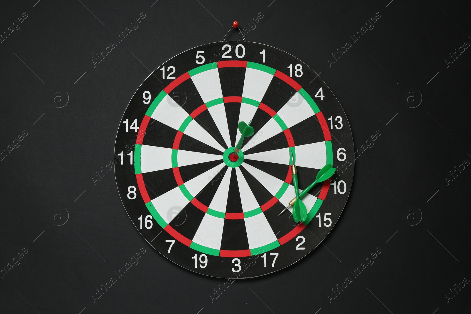 Photo of Dart board and green arrows on black background, top view