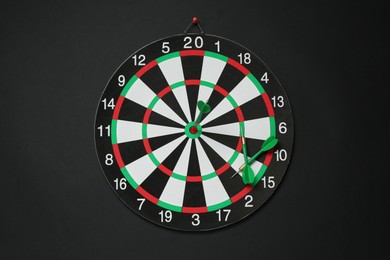 Photo of Dart board and green arrows on black background, top view