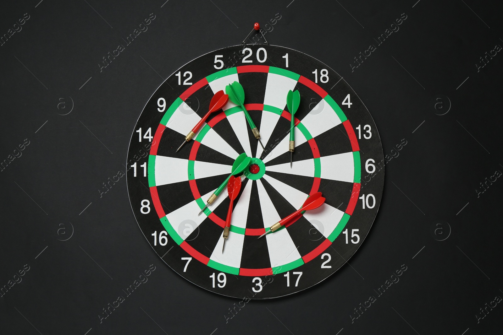 Photo of Dart board and colorful arrows on black background, top view