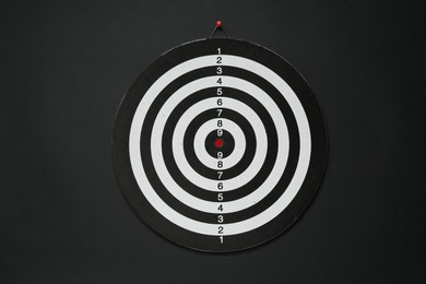 Photo of One dart board hanging on black wall