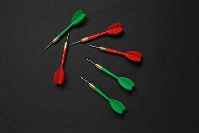 Photo of Colorful dart arrows on black background, flat lay