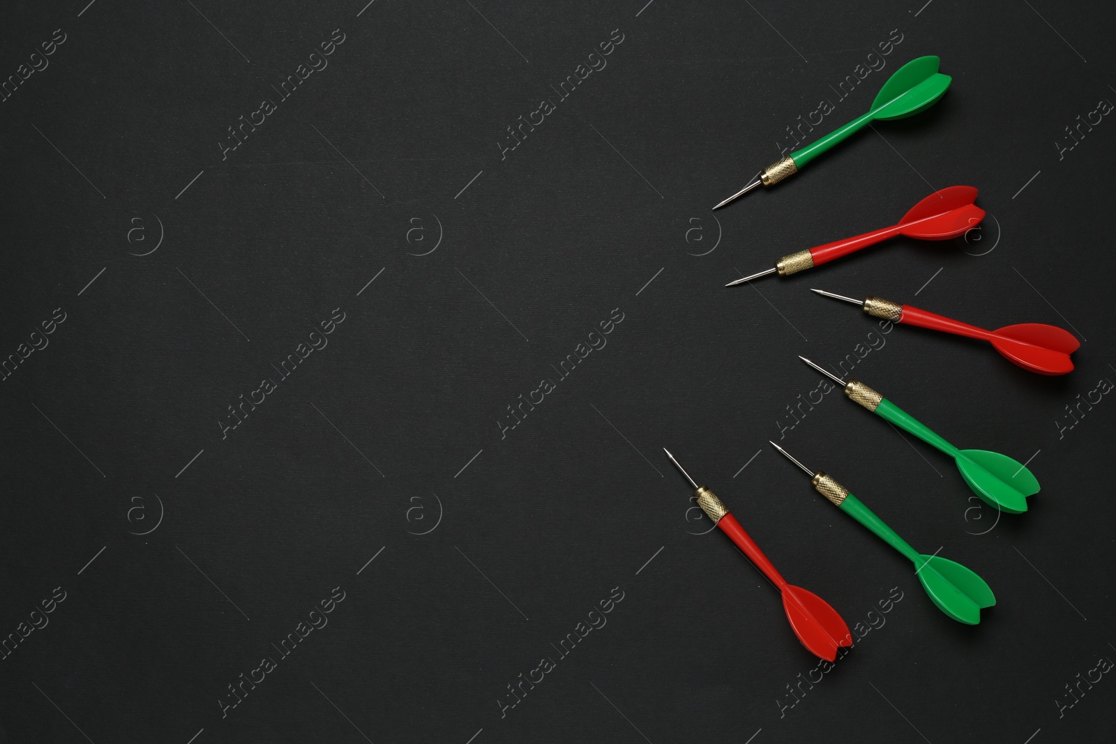 Photo of Colorful dart arrows on black background, flat lay. Space for text