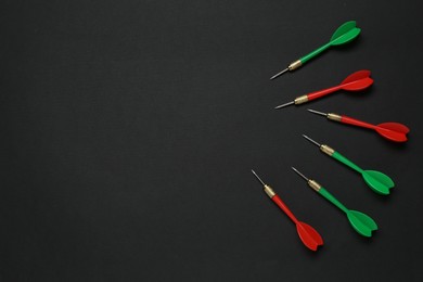 Photo of Colorful dart arrows on black background, flat lay. Space for text