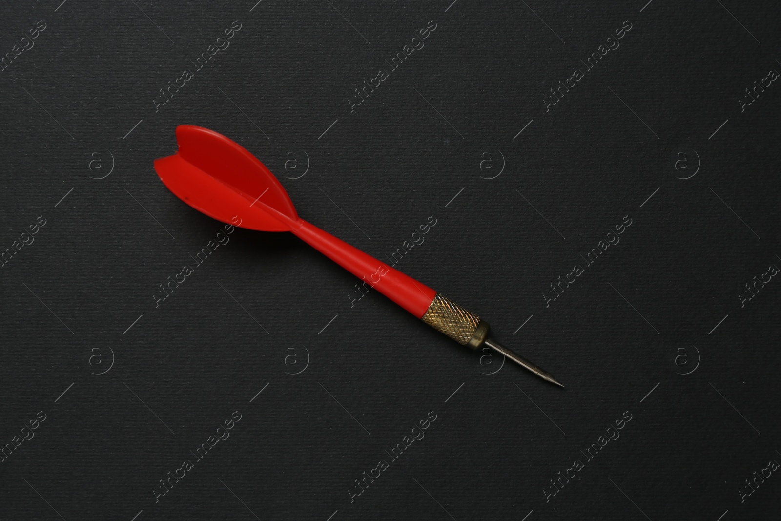 Photo of One red dart arrow on black background, top view