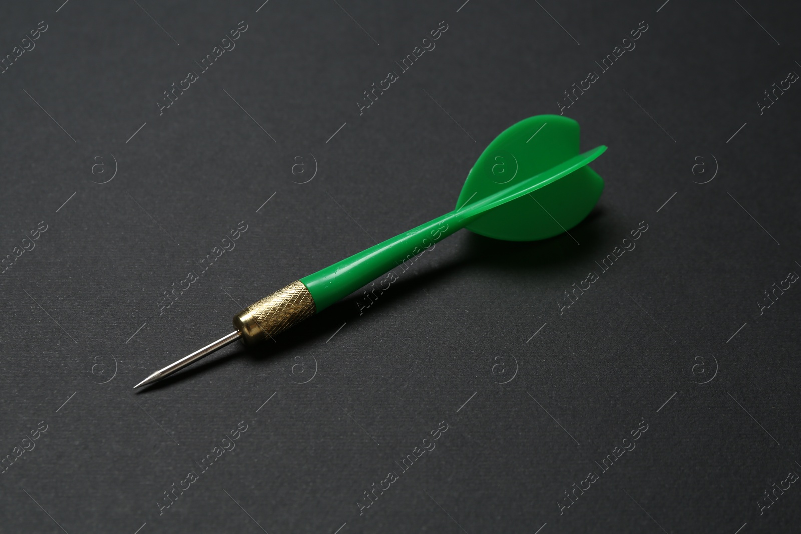 Photo of One green dart arrow on black background, closeup