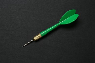 Photo of One green dart arrow on black background, top view