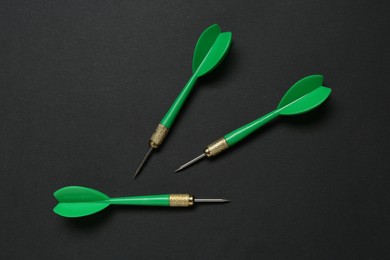 Photo of Green dart arrows on black background, flat lay