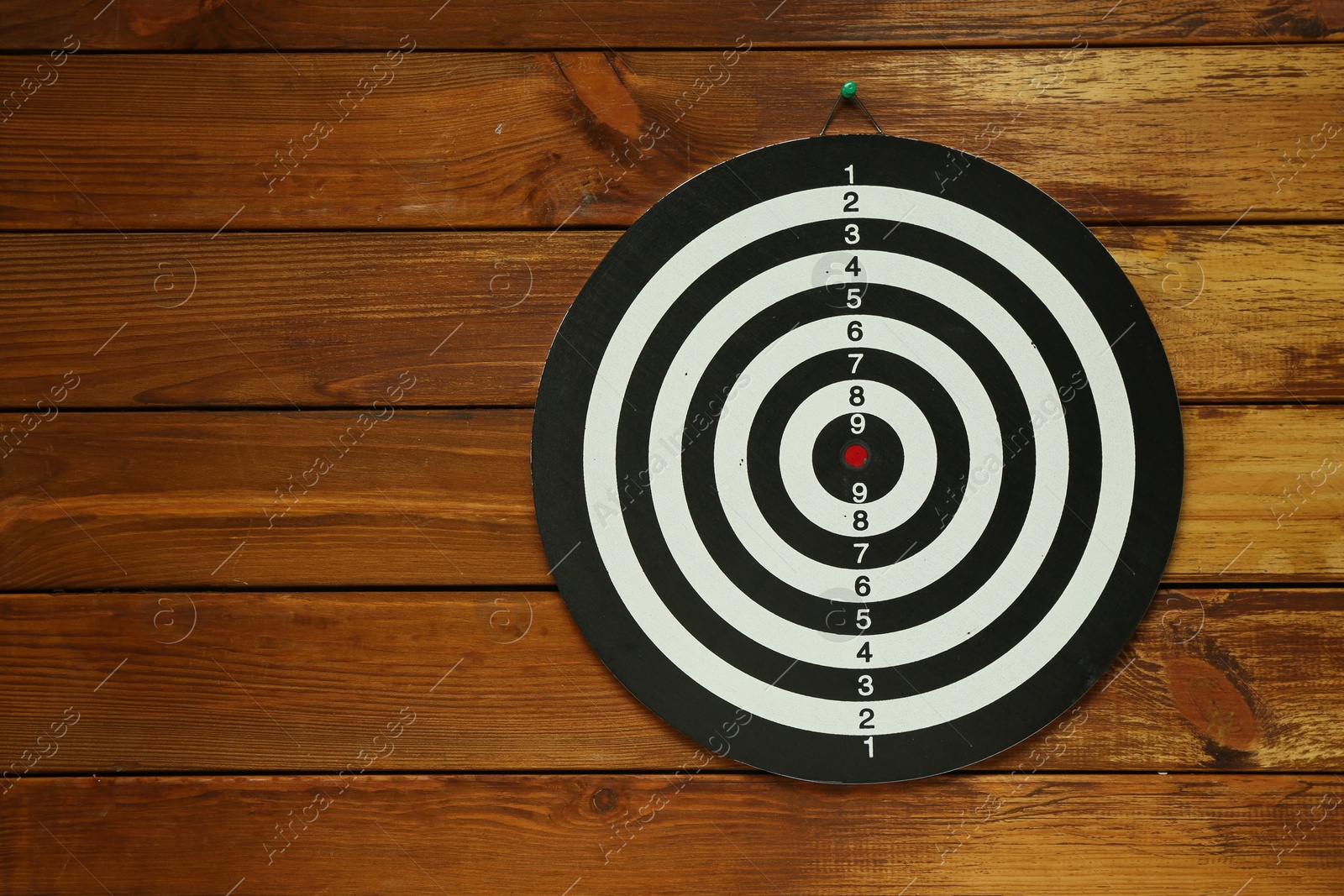 Photo of One dart board hanging on wooden background. Space for text