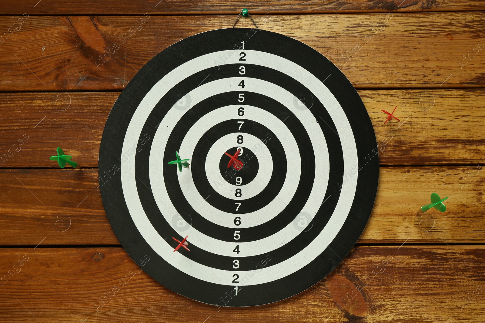 Photo of Dart board with colorful arrows on wooden background