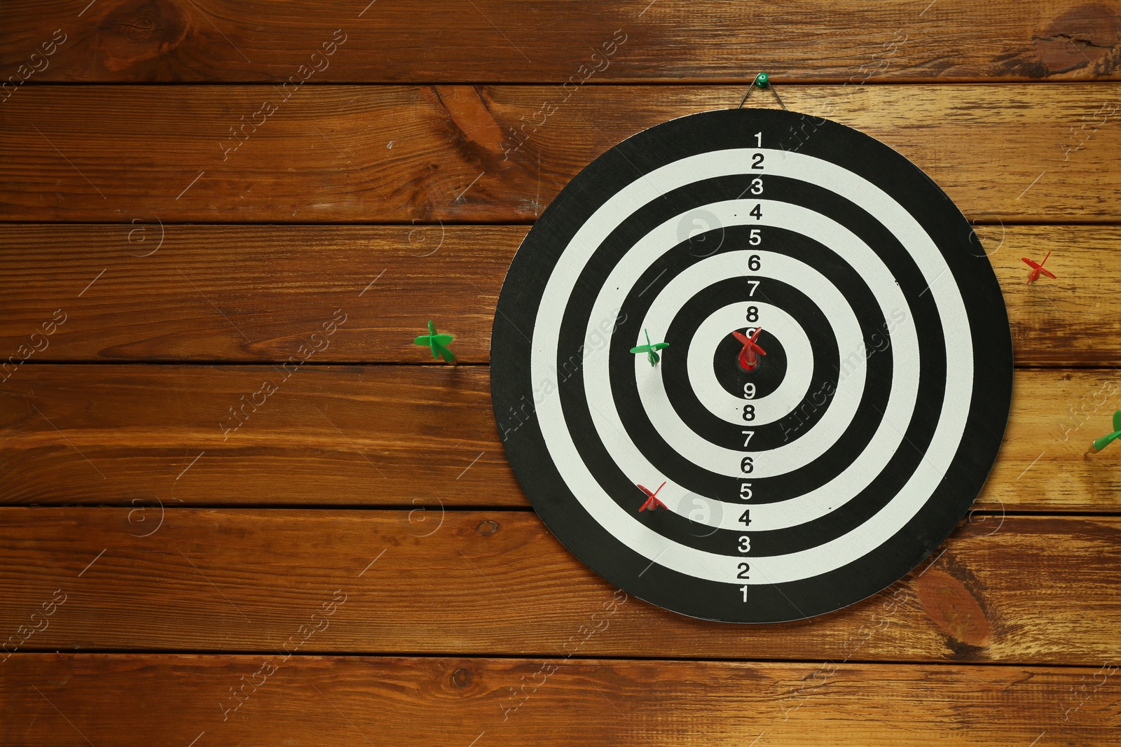 Photo of Dart board with colorful arrows on wooden background, space for text