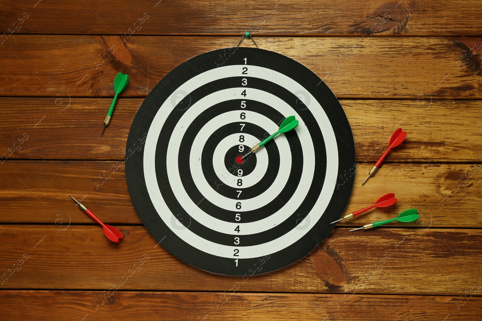 Photo of Dart board and colorful arrows on wooden background, flat lay