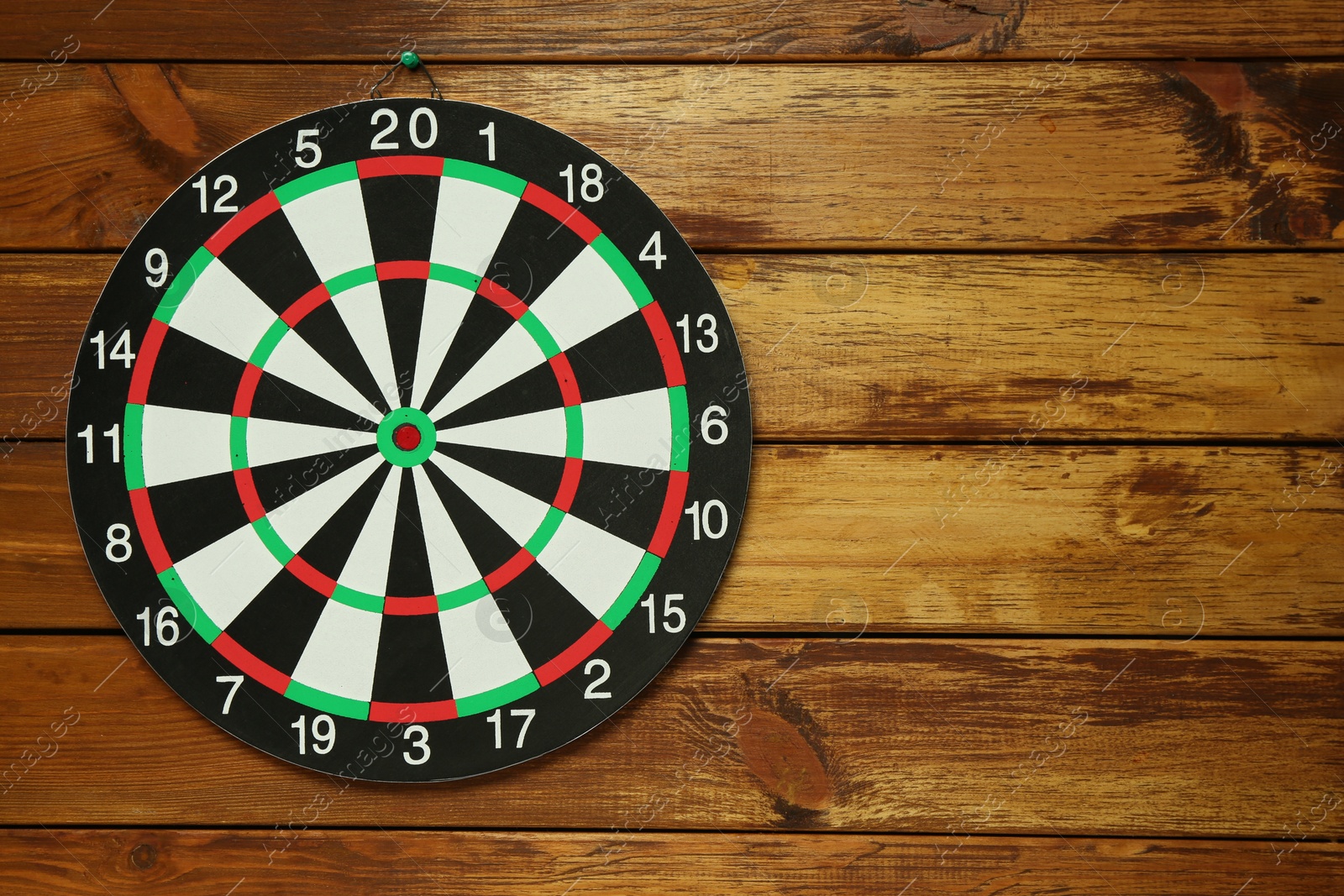 Photo of Dart board hanging on wooden background, space for text