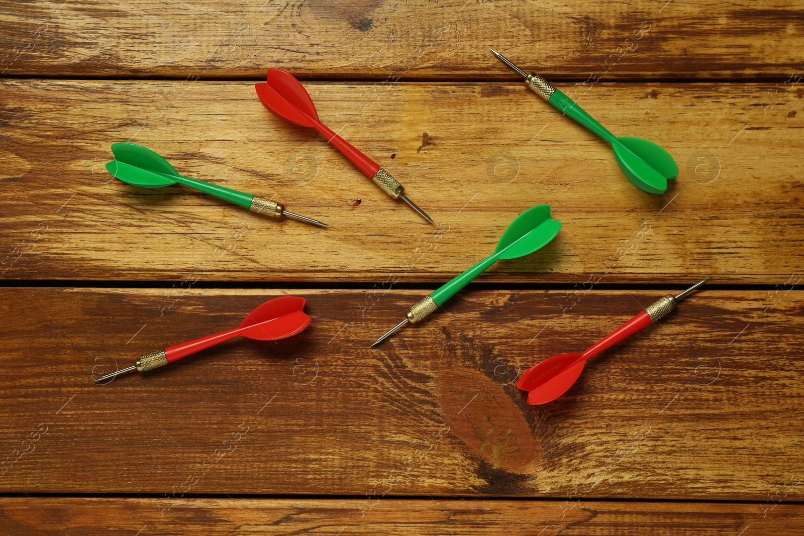 Photo of Colorful dart arrows on wooden table, flat lay