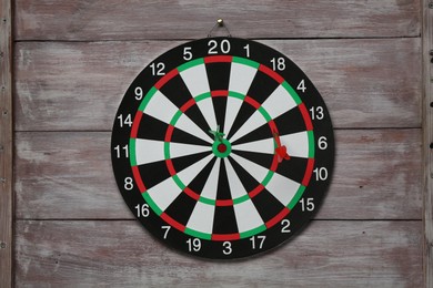 Photo of One dart board with colorful arrows on wooden rustic background