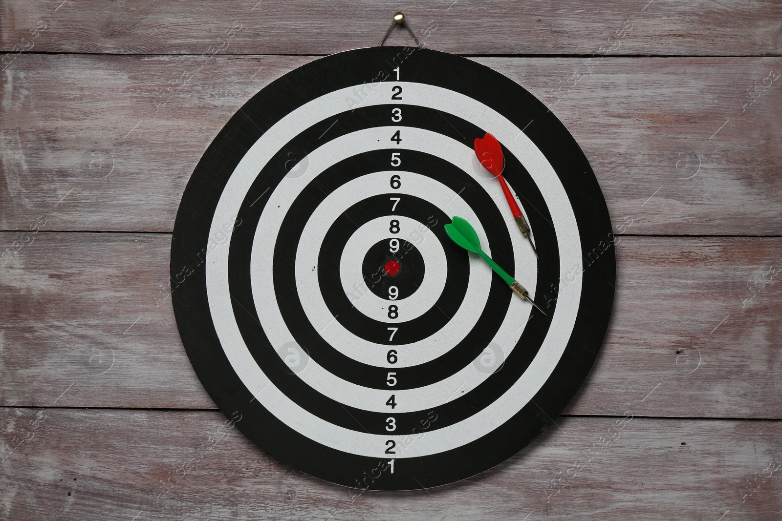 Photo of One dart board with colorful arrows on wooden rustic background, top view