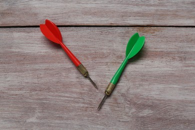 Photo of Colorful dart arrows on wooden rustic table, flat lay