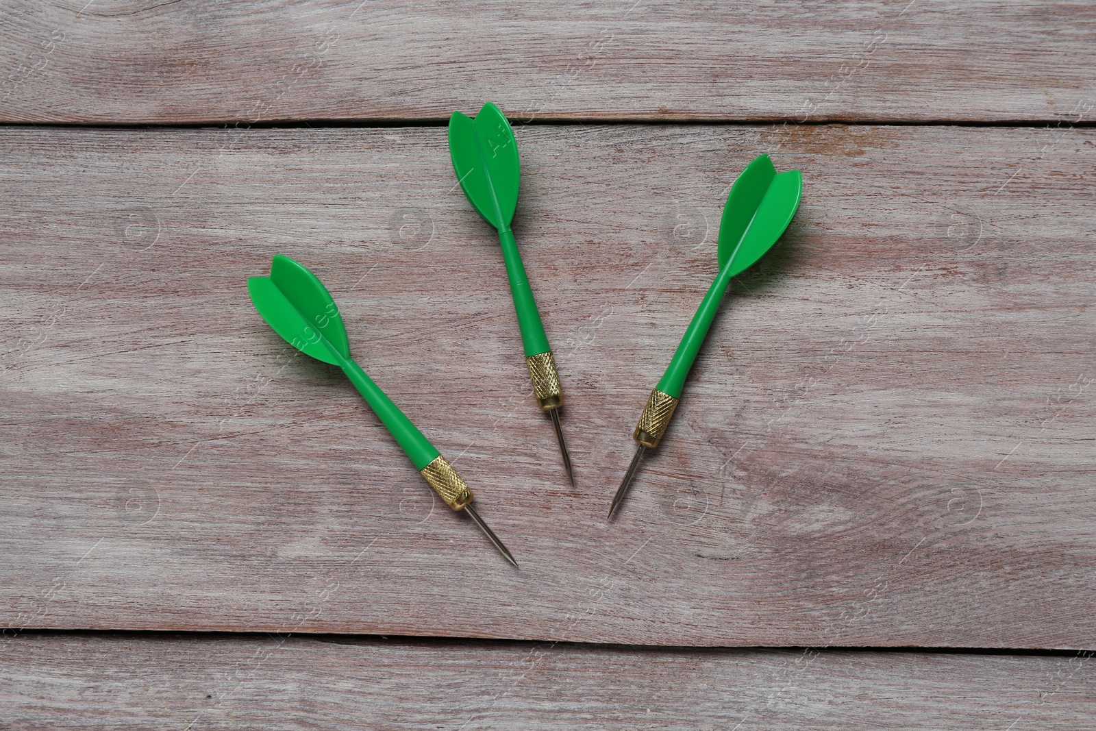 Photo of Green dart arrows on wooden rustic table, flat lay