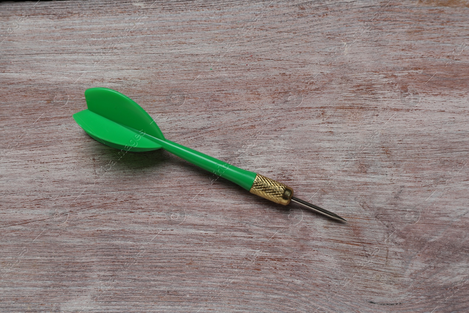 Photo of Green dart arrow on wooden rustic table, top view