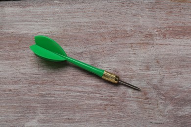 Photo of Green dart arrow on wooden rustic table, top view