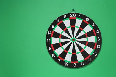 Photo of One dart board hanging on green wall, space for text