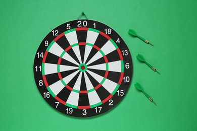 Photo of Dart board and arrows on green background, flat lay