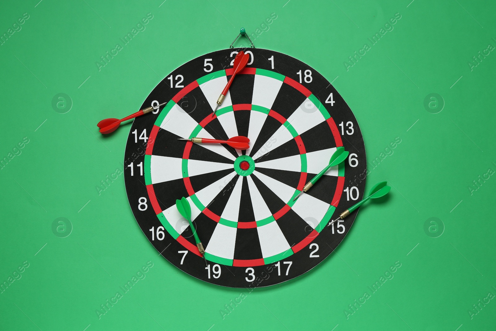 Photo of Dart board and colorful arrows on green background, flat lay