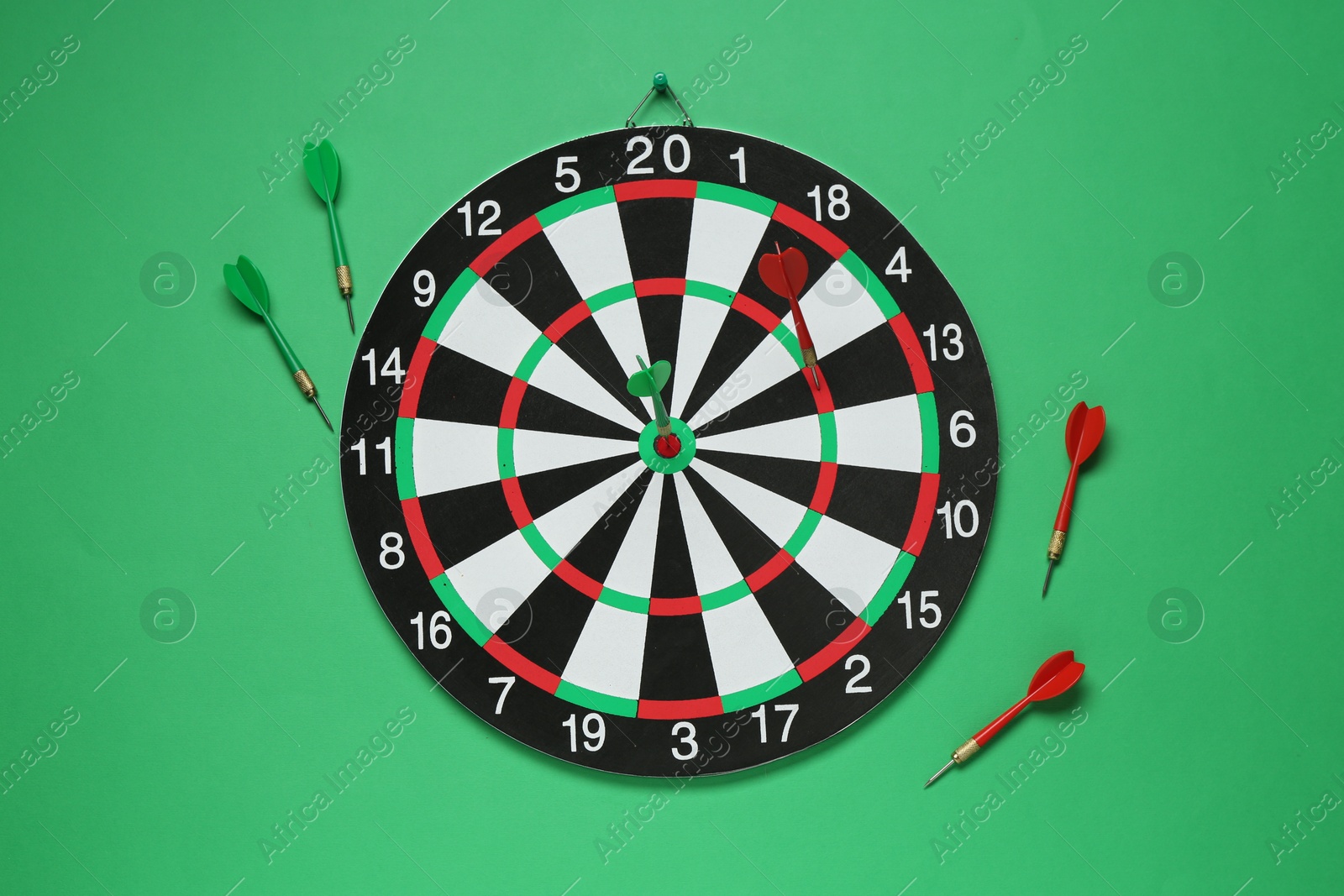 Photo of Dart board and colorful arrows on green background, flat lay