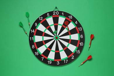 Photo of Dart board and colorful arrows on green background, flat lay