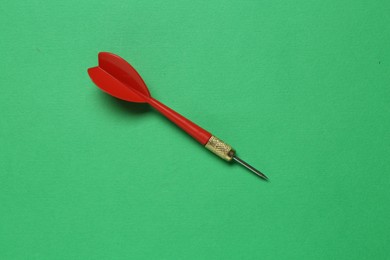 Photo of Red dart arrow on green background, top view