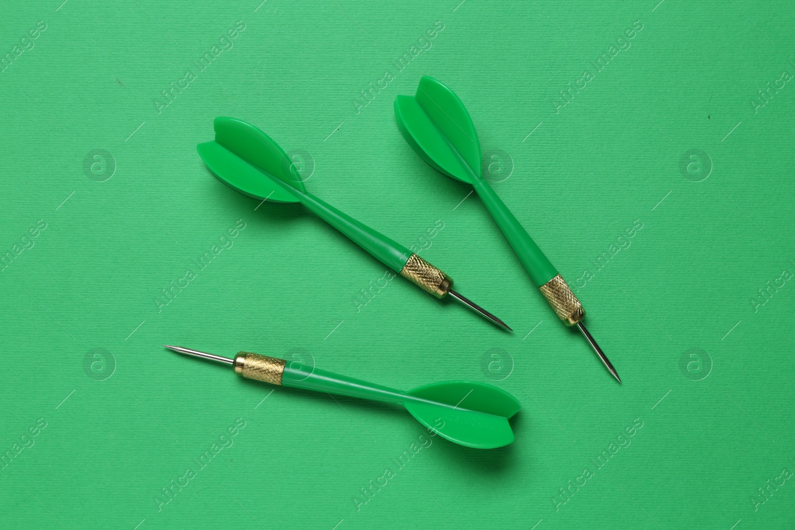 Photo of Dart arrows on green background, flat lay