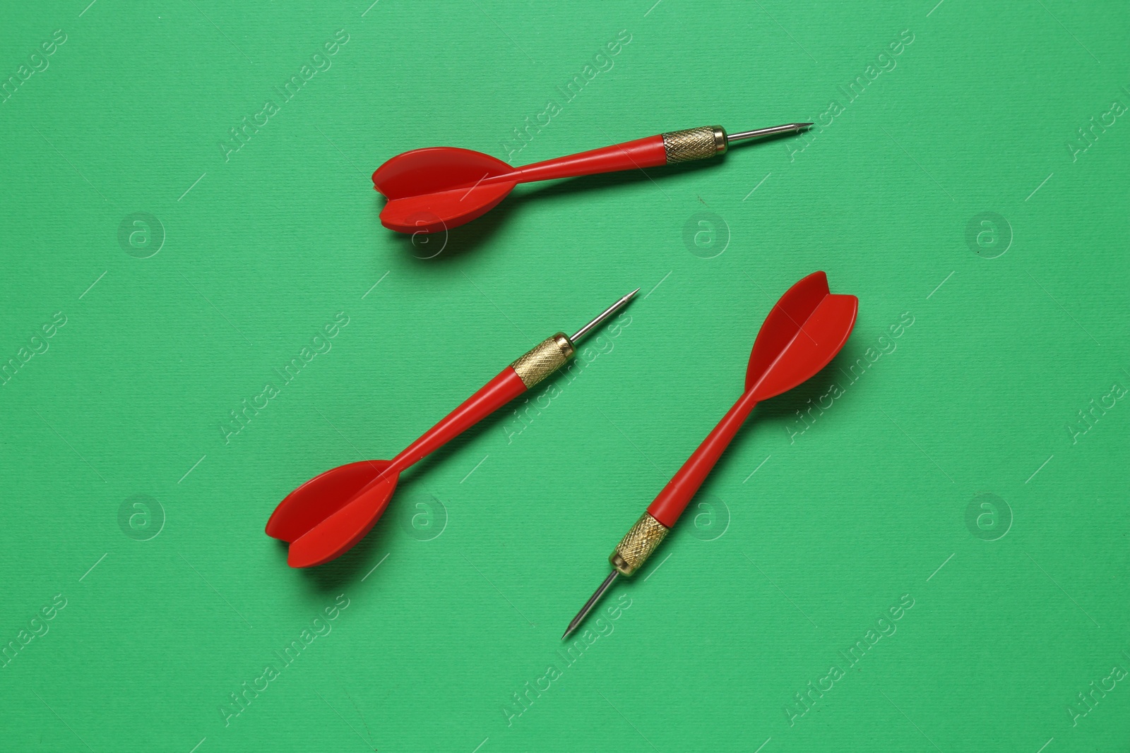 Photo of Red dart arrows on green background, flat lay