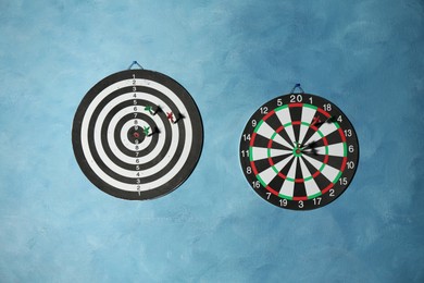 Photo of Dart boards with colorful arrows hanging on blue textured wall