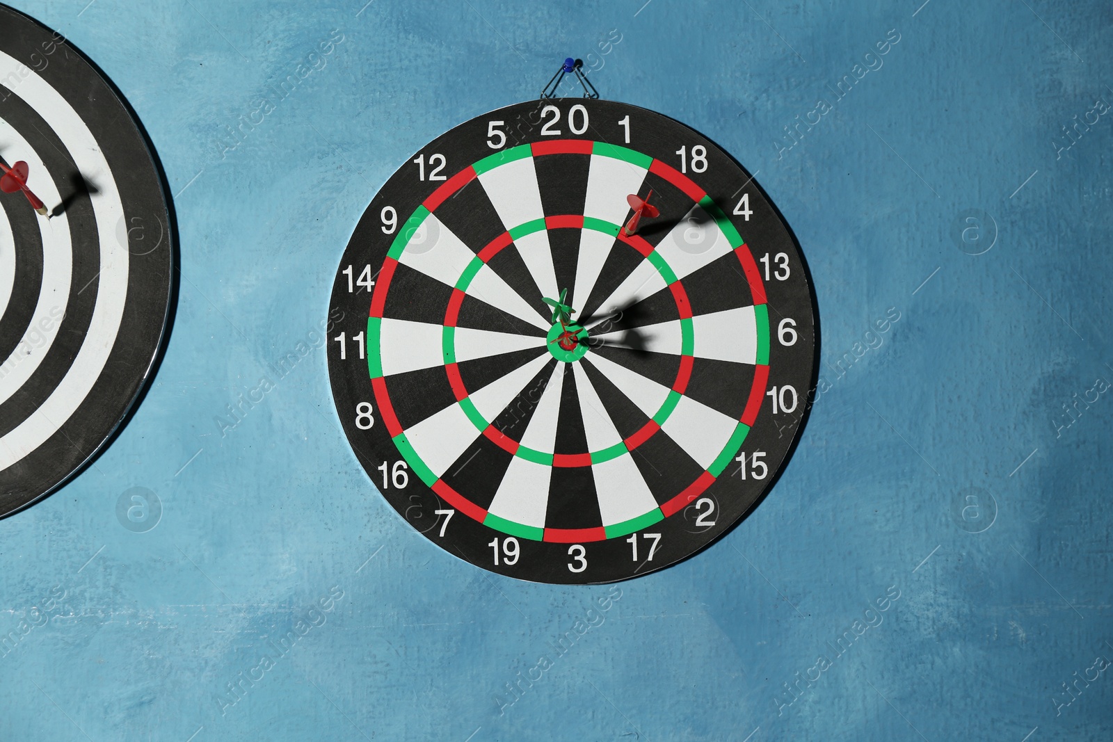 Photo of Dart boards with colorful arrows hanging on blue textured wall