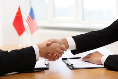 Photo of Diplomats shaking hands during meeting at wooden table indoors, closeup