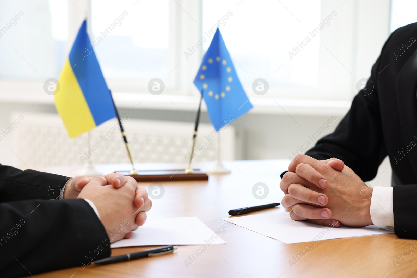 Photo of Diplomats negotiating during meeting at table indoors, closeup