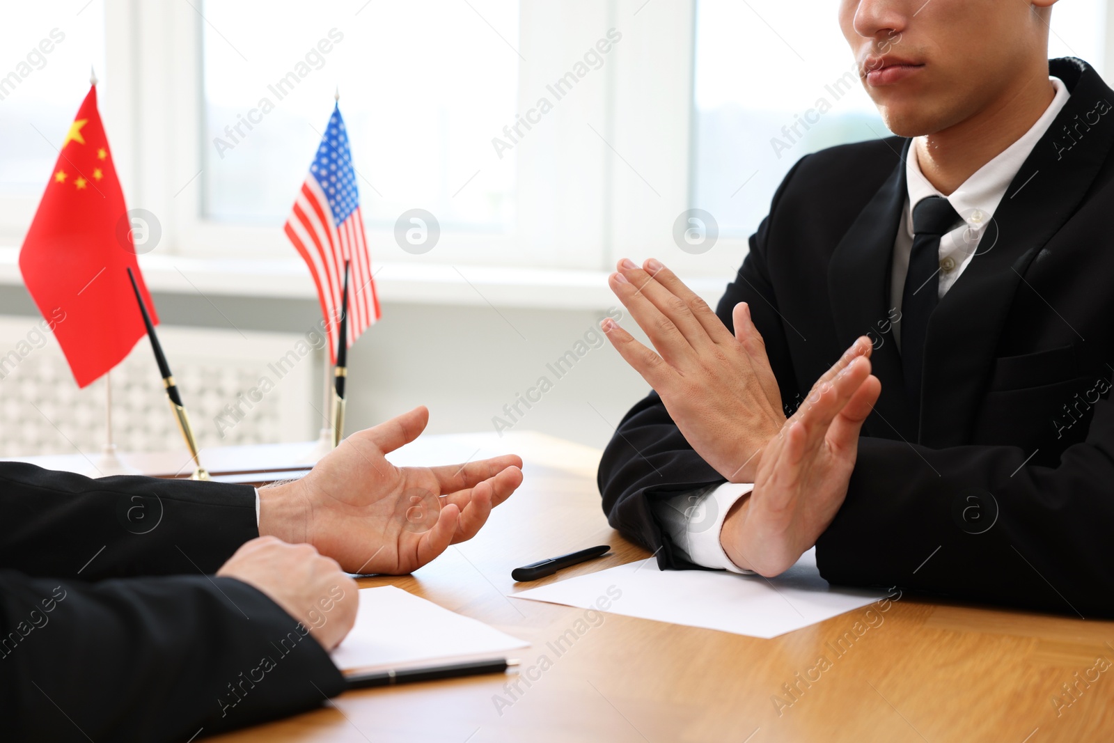 Photo of Diplomats negotiating during meeting at wooden table indoors, closeup