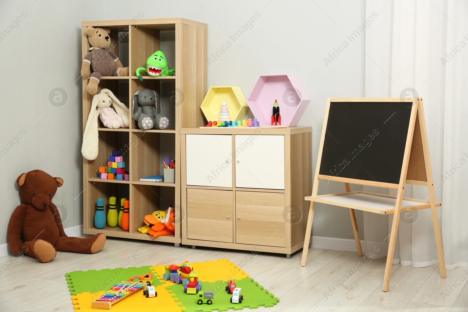 Photo of Beautiful kid's room interior with toys, blackboard and stylish furniture