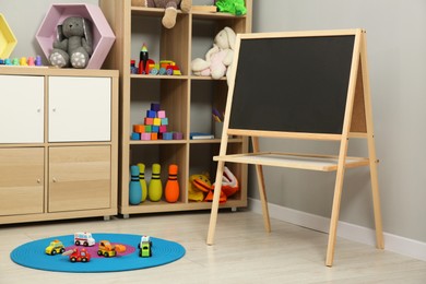 Photo of Beautiful kid's room interior with toys, blackboard and stylish furniture