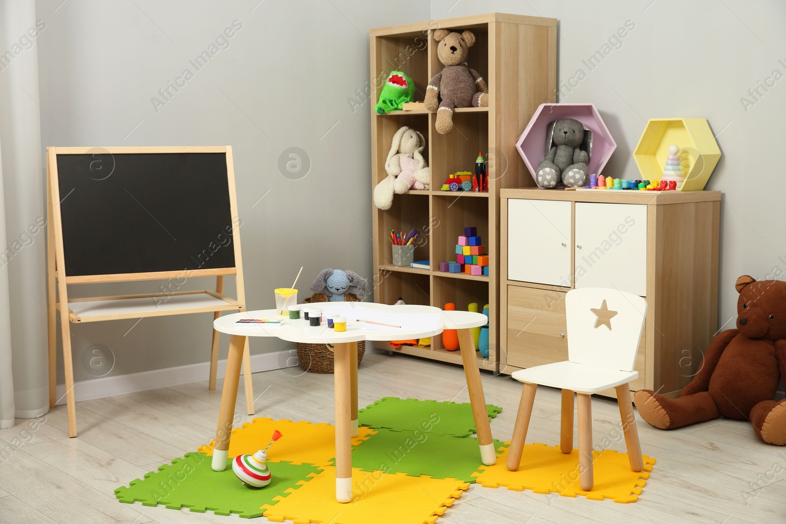 Photo of Beautiful kid's room interior with toys, paints and stylish furniture