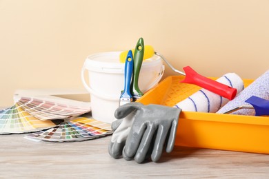 Photo of Different painter's tools on light wooden table. Decorating and design