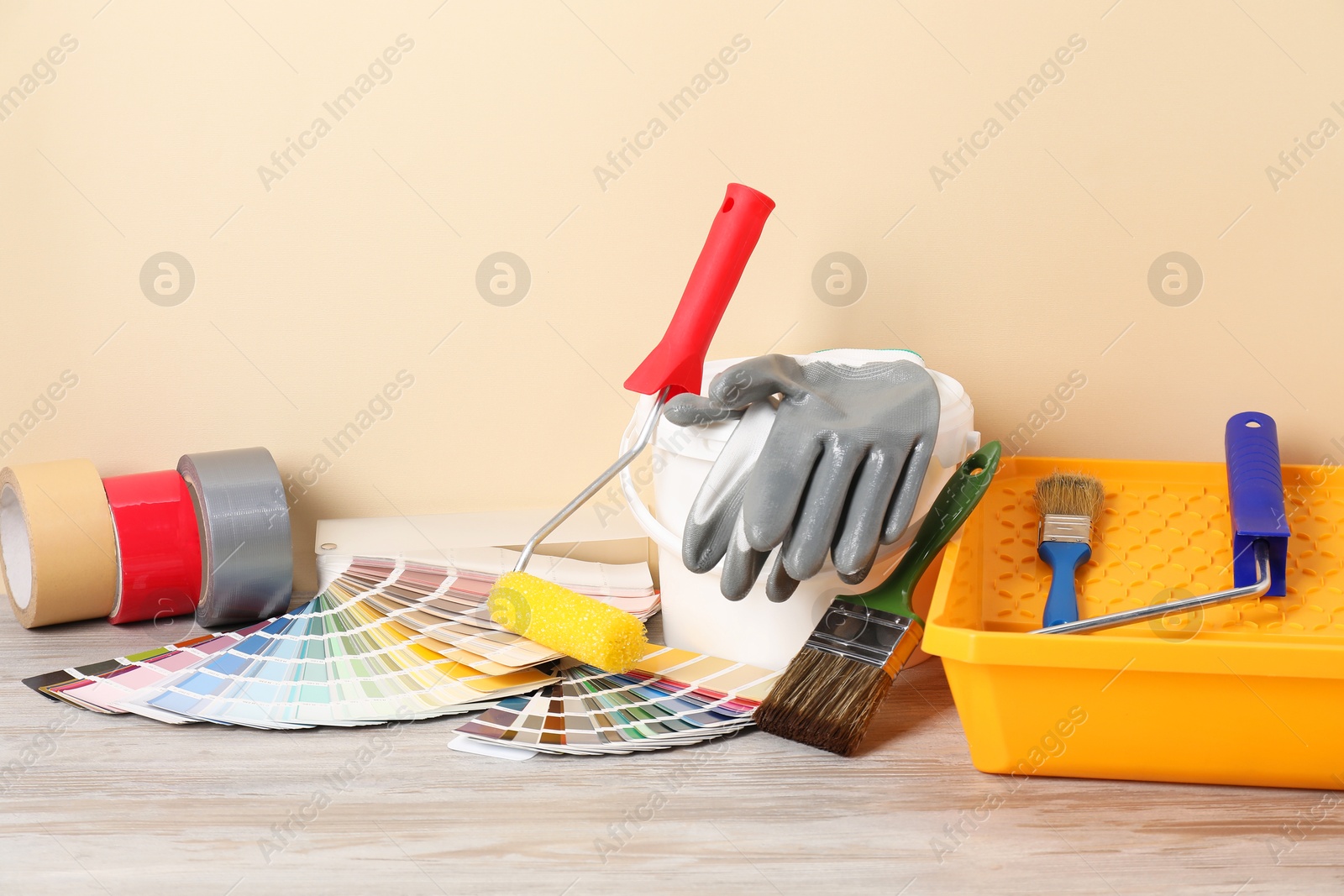 Photo of Different painter's tools on light wooden table. Decorating and design