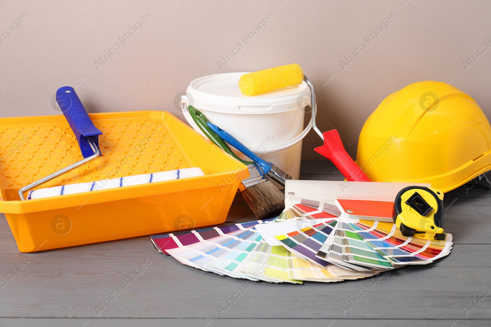 Photo of Different painter's tools on grey wooden table. Decorating and design