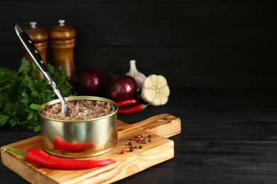 Photo of Canned meat in tin can and spices on wooden table, space for text