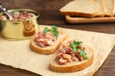 Photo of Sandwiches with canned meat and parsley on wooden table, closeup