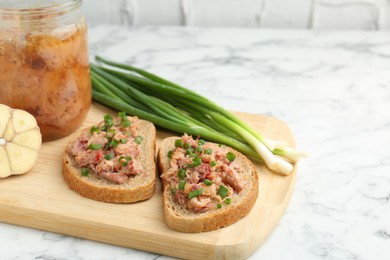 Photo of Sandwiches with canned meat and green onions on white marble table, closeup