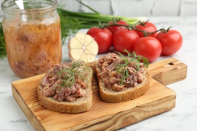 Photo of Sandwiches with canned meat, dill, garlic and tomatoes on white marble table, closeup